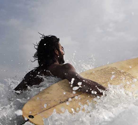 man in ocean with surfboard