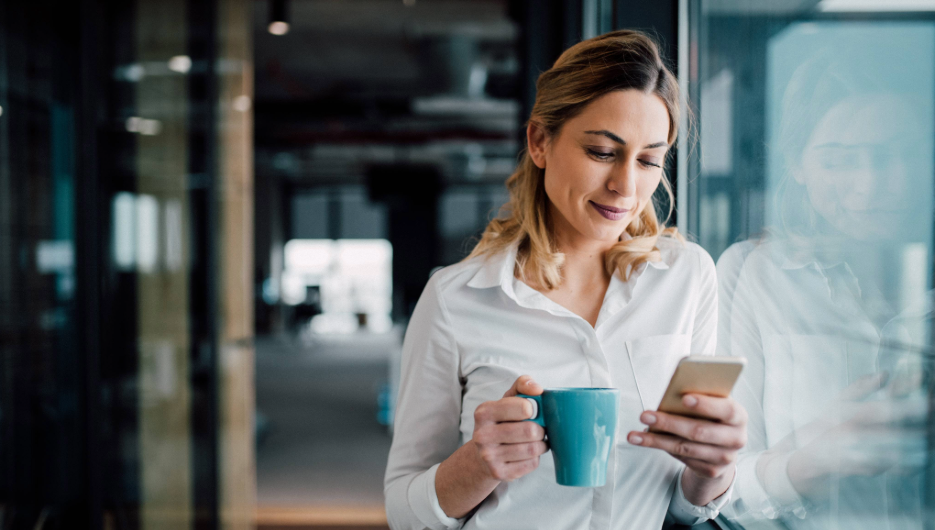 mujer con café y móvil en oficina