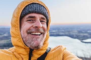 Hombre sonriente en lo alto de una montaña
