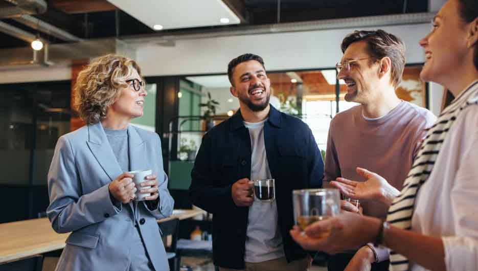Happy colleagues having a coffee break in an office. Group of business people having a conversation in a workplace. Business professionals working in a startup.