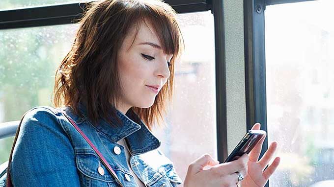 mujer joven en autobús con el móvil